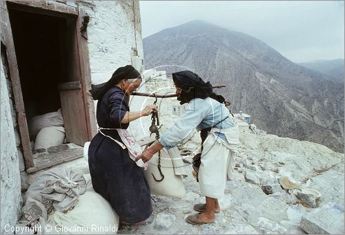 GREECE (Dodecanese) Karpathos Island - GRECIA (Dodecanneso) Isola di Scarpanto - Olimbos - antico paese arroccato sul crinale ed isolato a nord dell'isola - le donne con i sacchi di farina prodotta dall'antico mulino a vento