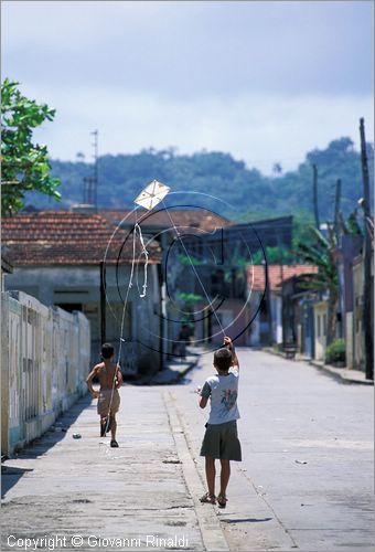 CUBA - Baracoa - la prima citt fondata sull'isola da Diego Velazquez tra il 1510 e il 1511 - scorcio in una via periferica con un bambino che gioca con un aquilone